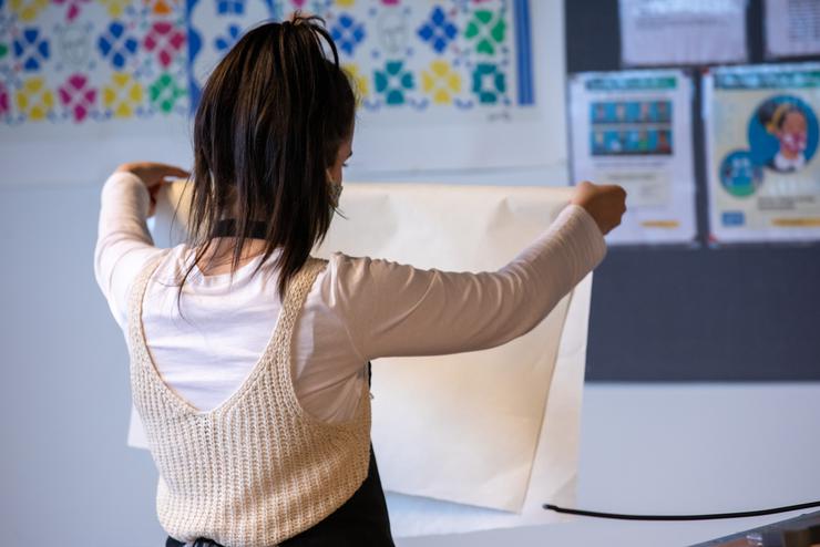 A printmaking student looks at a large piece of paper.