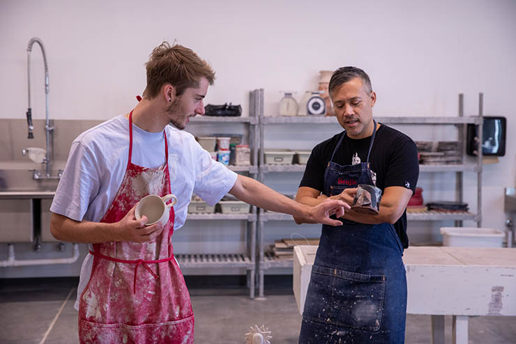 an art and design faculty member reviews a ceramic piece with his student