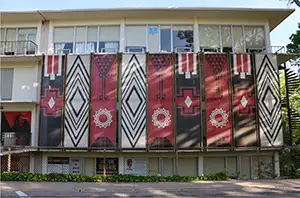 an artwork installation on a building's balcony railing featuring large banners patterned in red, black and white