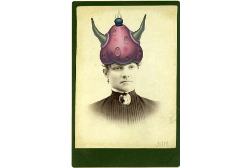 A sepia-colored photo of a woman wearing a black top with a pink object with green horns painted on her head. 