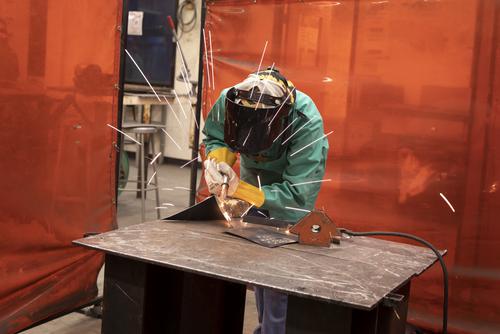 a student works in the sculpture workshop using a welding torch with sparks flying outward