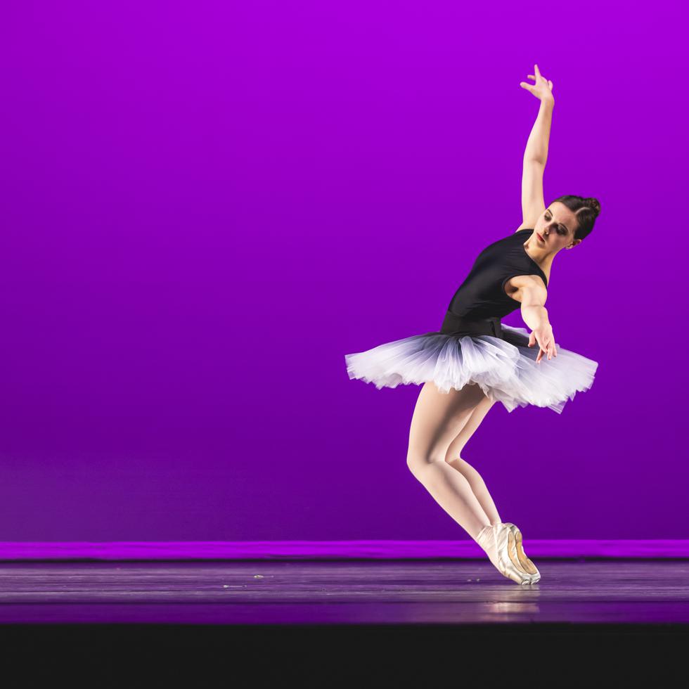 A student dances on stage against a purple background in the Bedell Performance Hall.  