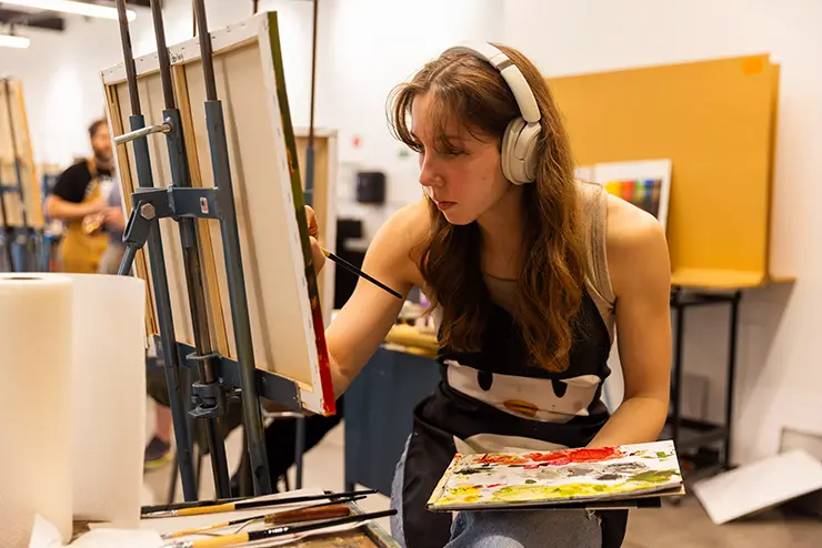 a semo painting student sits at her easel and works on a class project as a part of the experiential learning program
