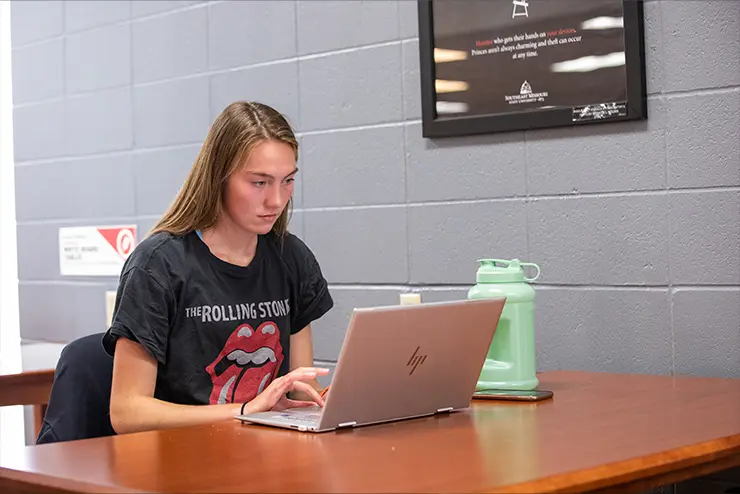 Student sitting in the library working on her computer at SEMO a top missouri school for experiential learning