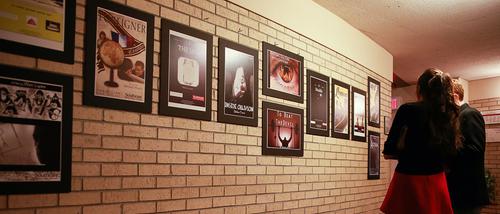 Two audience members at the Faultline Film Festival view film posters. 