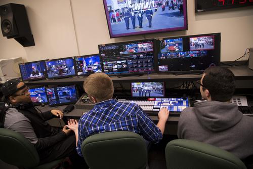A group of mass media students view the current production taking place at the Rust Center for Media on multiple screens.