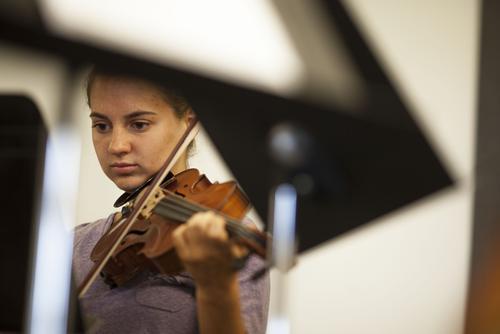 Student plays string instrument in front along with a piano