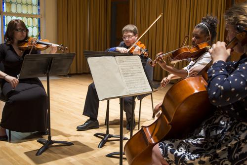 Students read music and play their string instruments.