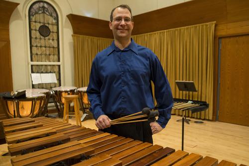 Dr. Shane Mizicko stands in front of musical instrument