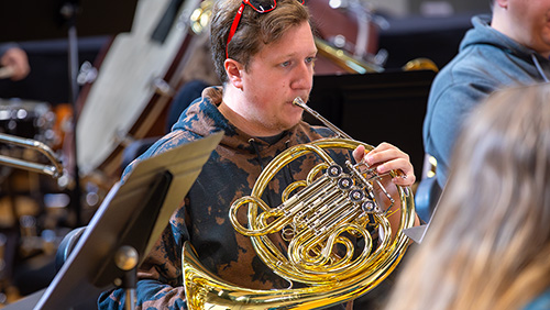 A student playing the French horn.