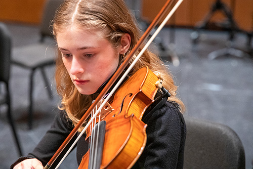   Student in the Symphony Orchestra plays the violin.  