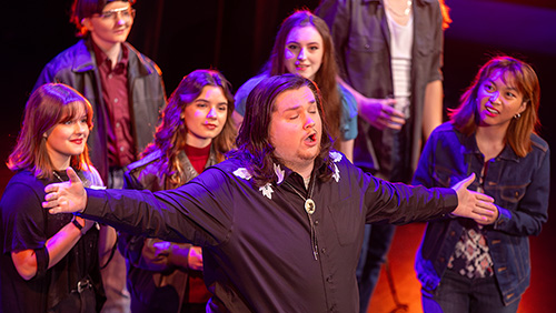 A semo student sings during a production in a cowboy look.