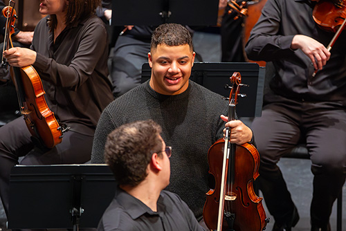 A student in the string Symphony talks to another student at the performance.