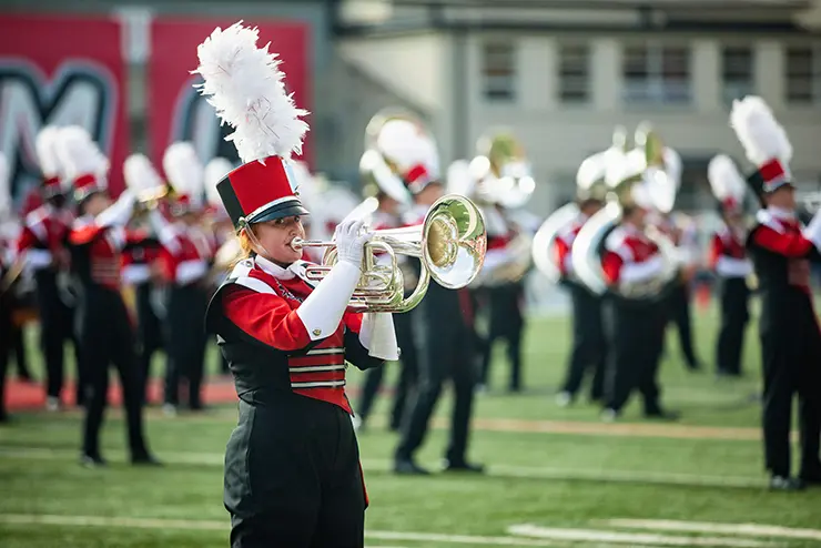 the SEMO marching band performs on Houck field during a football game, wearing their marching band uniforms