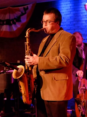 chip mcnell performing with his saxophone on a blue and orange lit stage