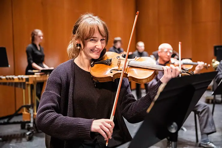 a SEMO orchestra student smiles at the photographer while playing her violin