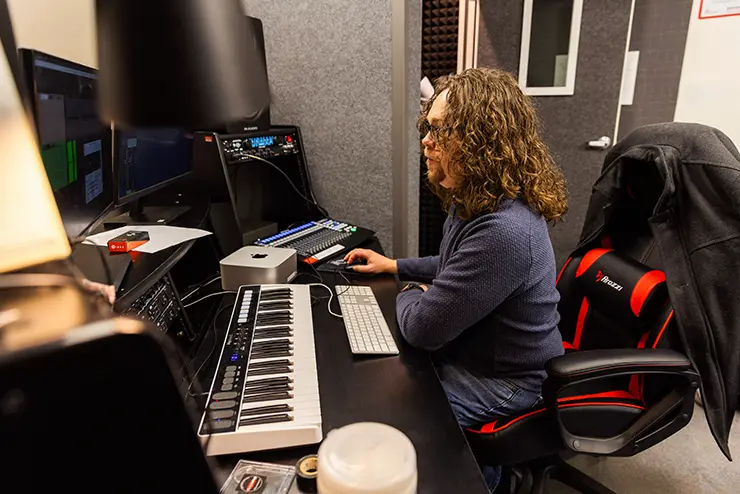 a SEMO student sits at a desk full of sound and recording equipment in the recording studio