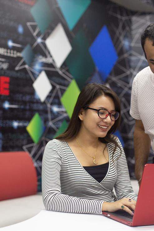 Cybersecurity students smile while working on a laptop in the Cyber Range.