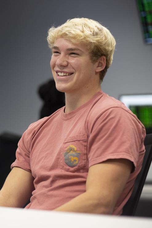 A business student smiles while working with peers in a classroom.
