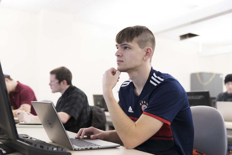 Students getting their Graduate Certificate in Cybersecurity, work on the computer in class.