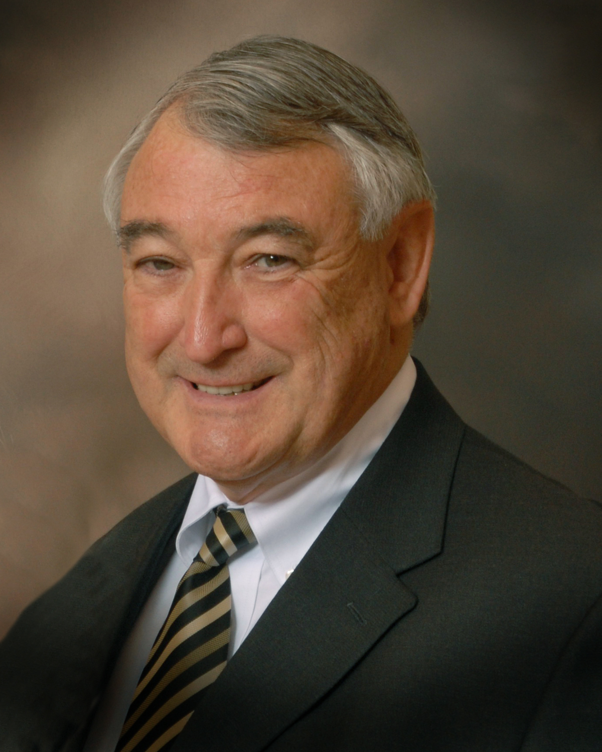 Douglas C. Greene smiles, wearing a suit and tie