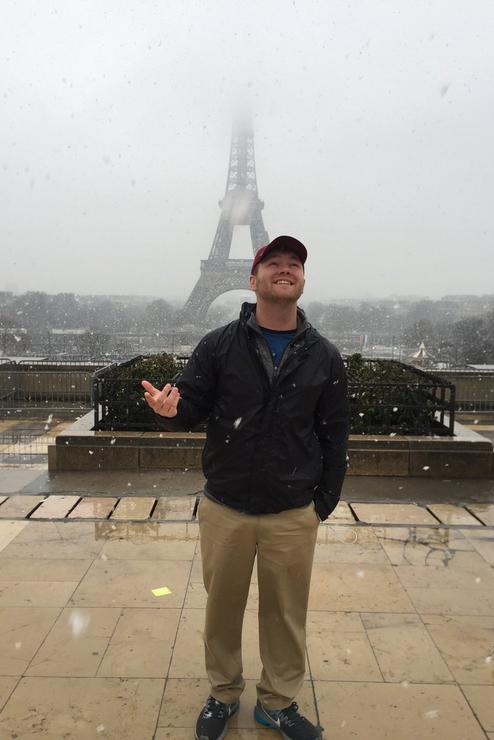A SEMO student, studying abroad, stands in Paris with the Eiffel Tower in the background. 