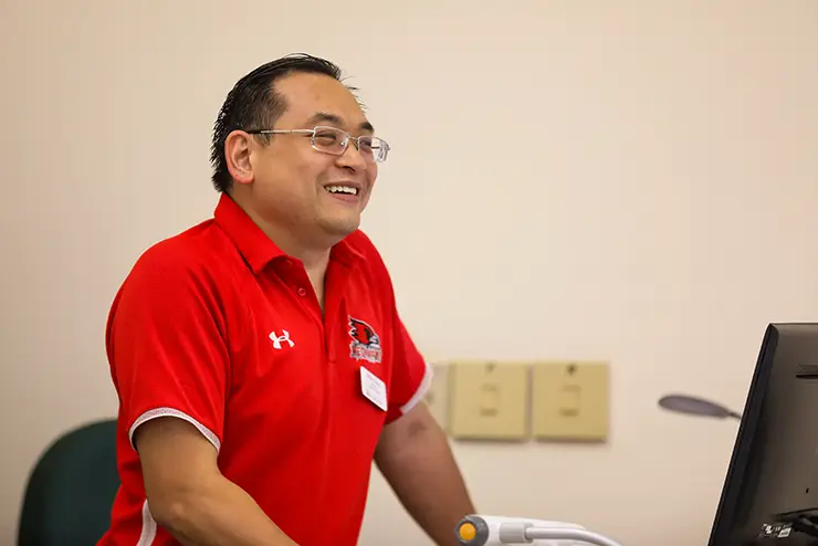 SEMO faculty member Ethan Chou smiles and laughs while standing at the front of a class