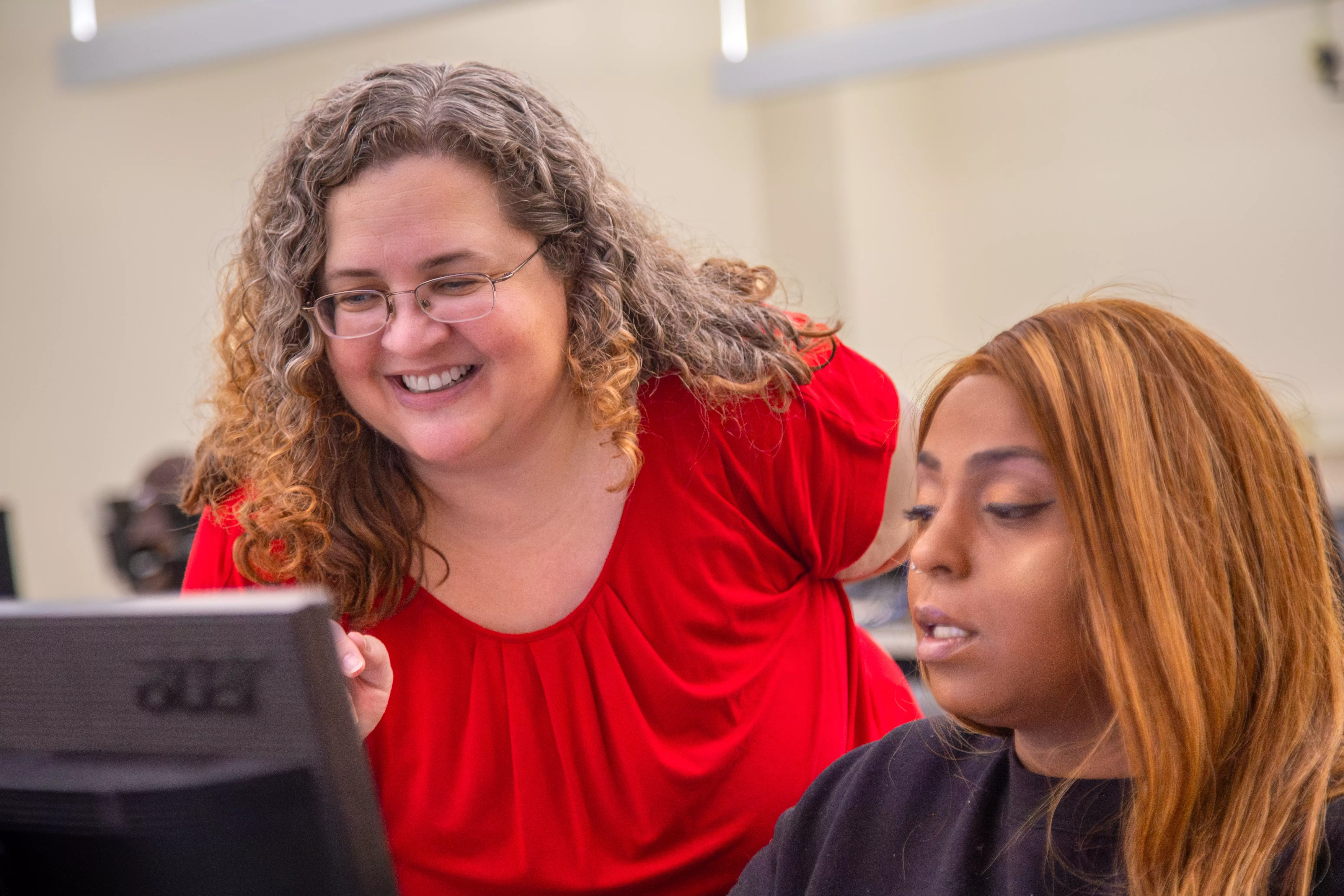 management professor showing a student something on her computer smiling