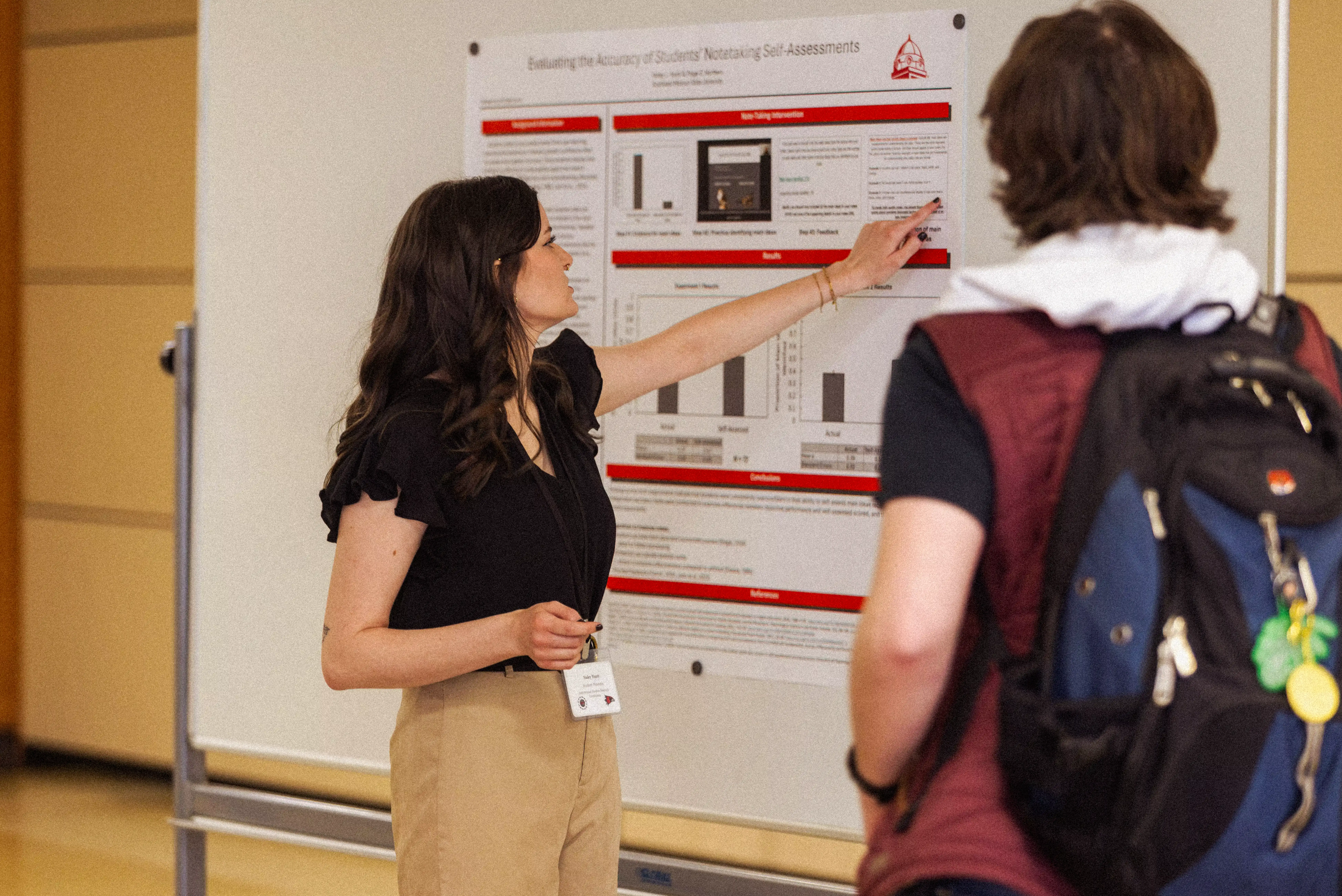 management student pointing at her display during a conference getting real world experience