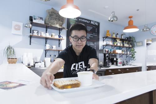 A hospitality management internship student puts food on a countertop while gaining field experience.