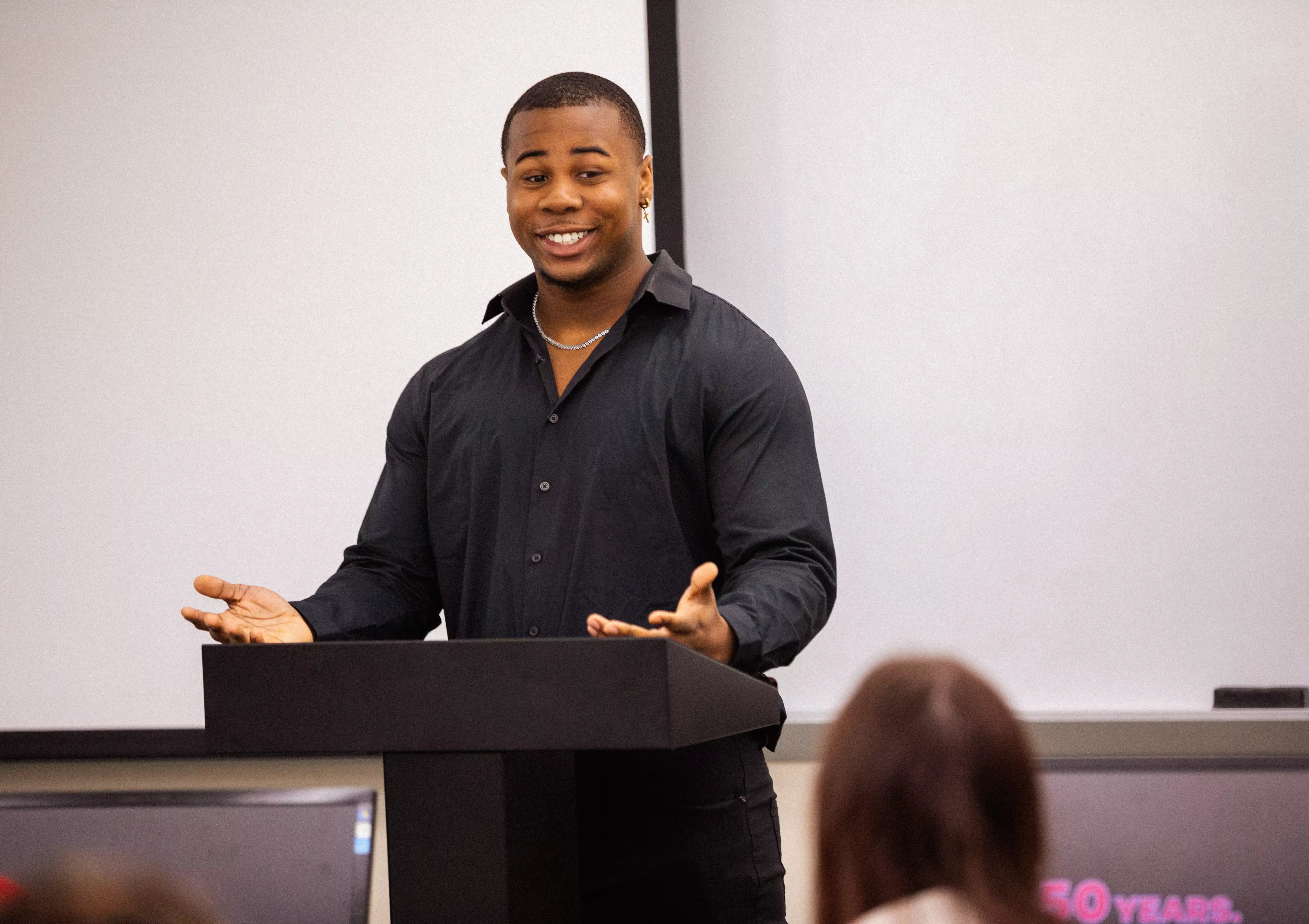 student presenting research based project presentation in management class