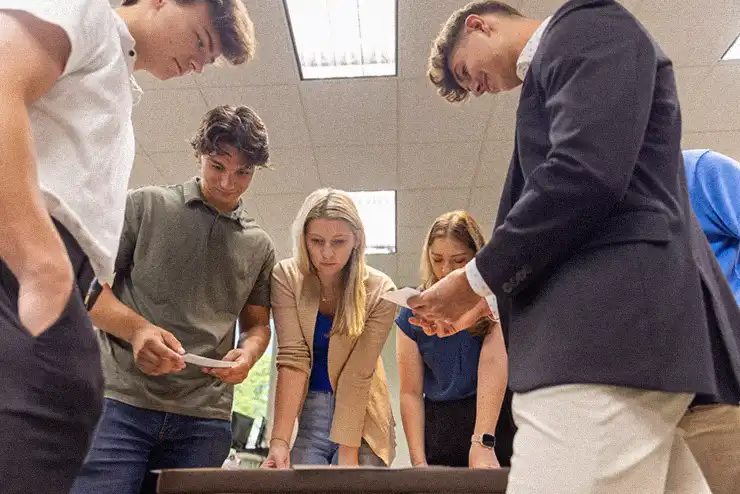 Students in the marketing degree program standing in a circle during class selecting names for a group project.