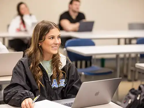 A marketing degree program student is intently watching her professor in class. 