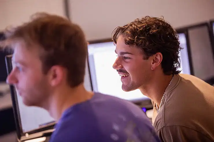 two students utilize marketing platforms on in the marketing lab at SEMO and smile at their screens while they experience hands-on learning.  