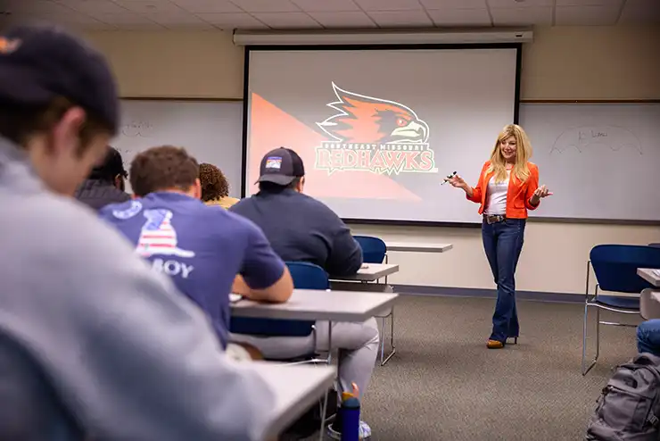 Professor teaches to class of marketing majors wearing a red blazer. 