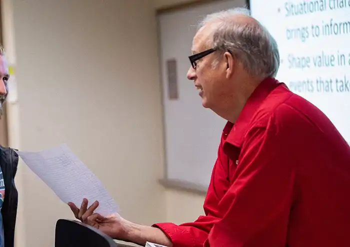 professor scott thorne provides a student with faculty mentorship in marketing at the front of his classroom.