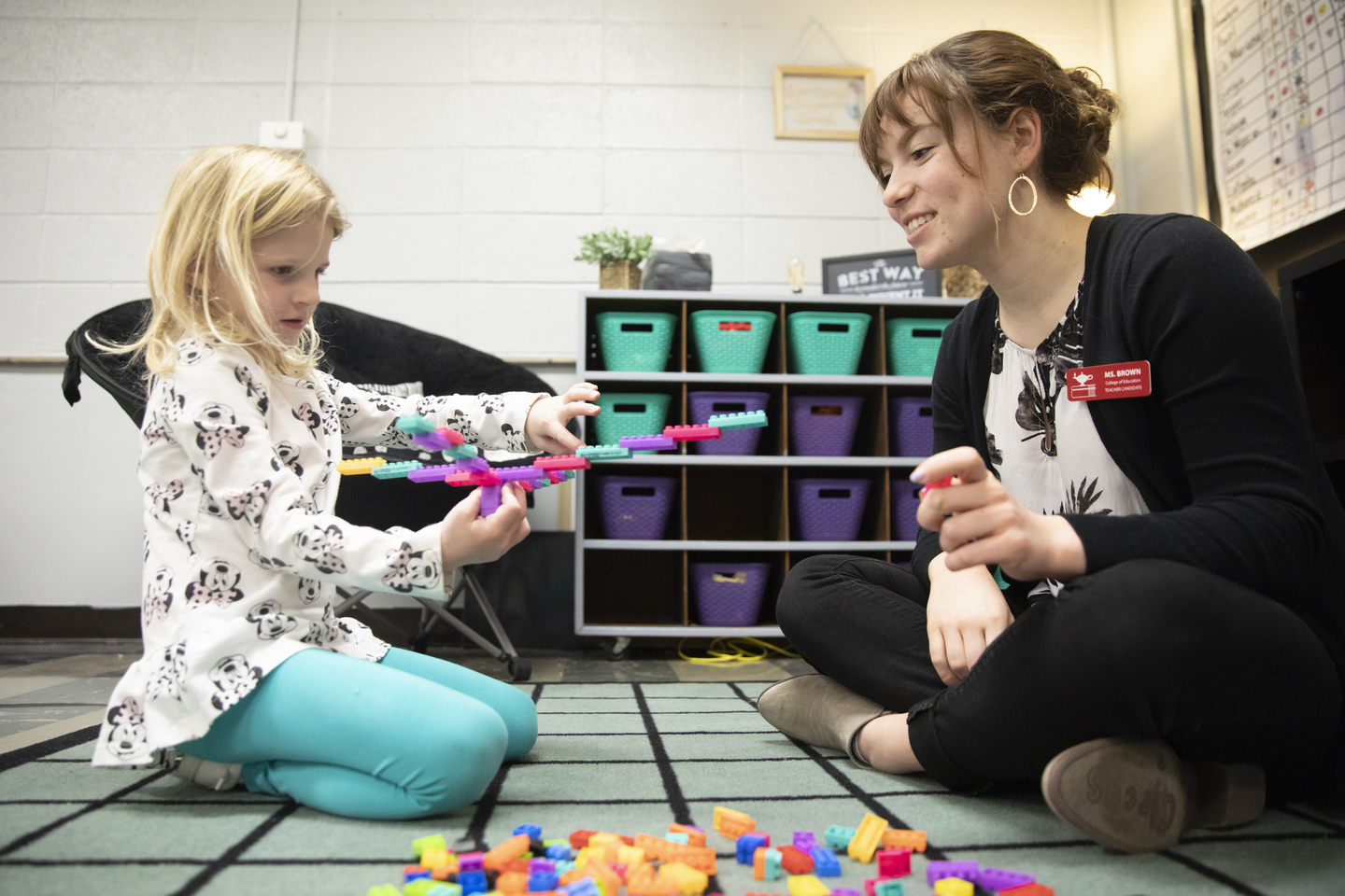 A student teacher smiles while working with a child at a local elementary school.