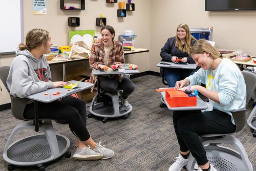 Students converse while working at desk inside the EDvolution Center.
