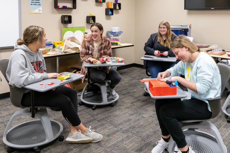 Students converse while working at desk inside the EDvolution Center.  