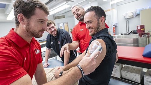 One student demonstrates a tool on another student.