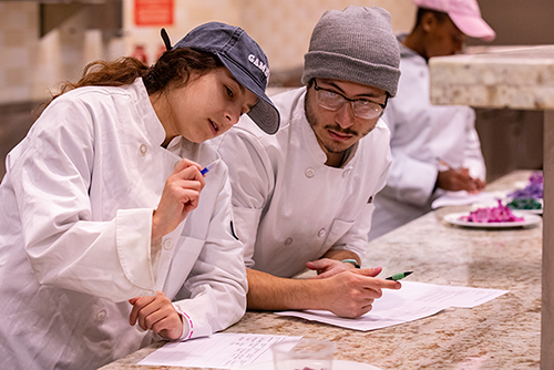 bachelor of science in nutrition students fill out sheets during a lab.