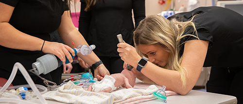 A Respiratory Therapy student practices on a baby dummy