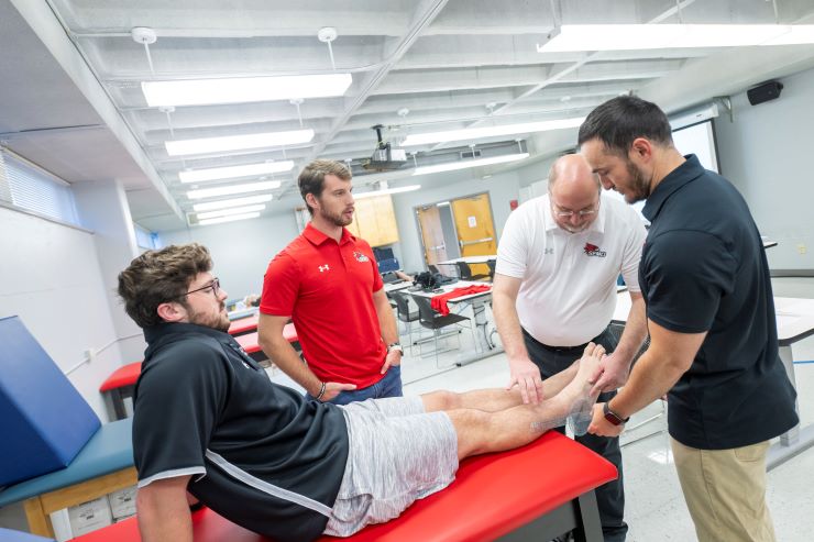 Athletic training students examine each other in a lab.