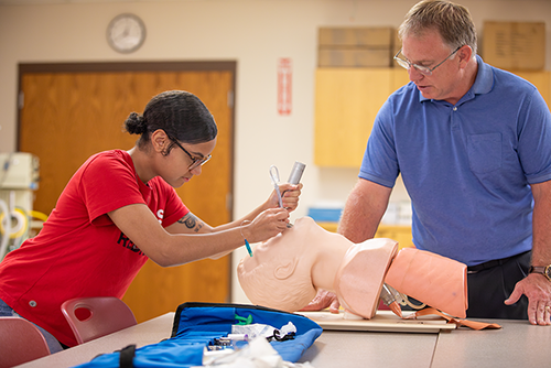A Respiratory therapy student practices on a dummy head.