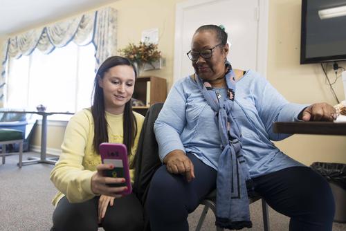 A student squats down to show something on their phone to an individual at the Hoover Center.