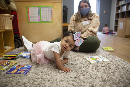 A Child and Family Studies student working at the University School for Young Children sits with a child.