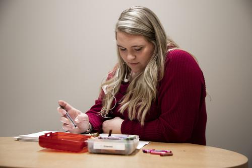 A Communication Disorders student looks at their notebook during a session.  