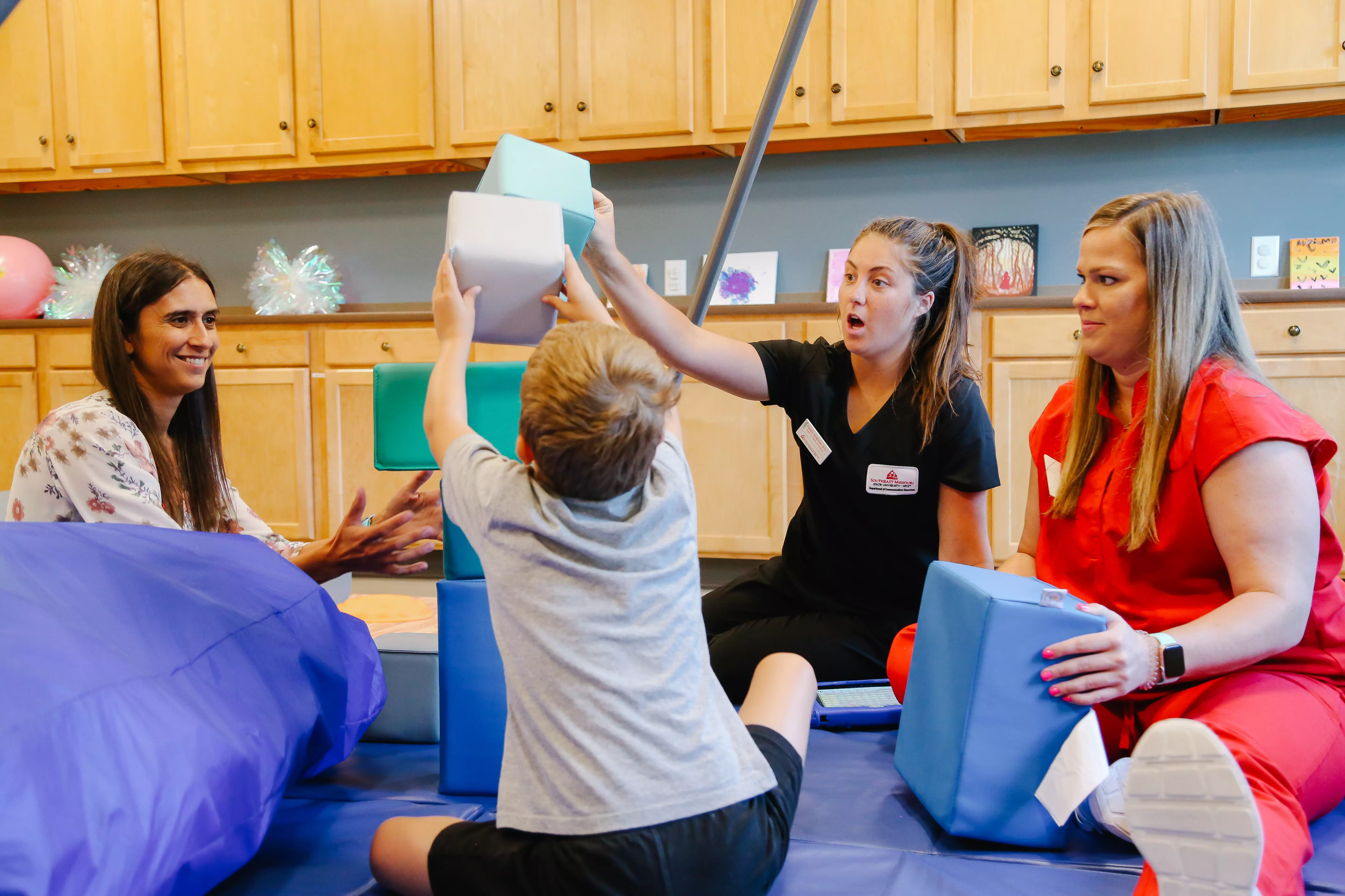 Communication disorders degree students in their clinical space therapy room applying their skills from the program with a child