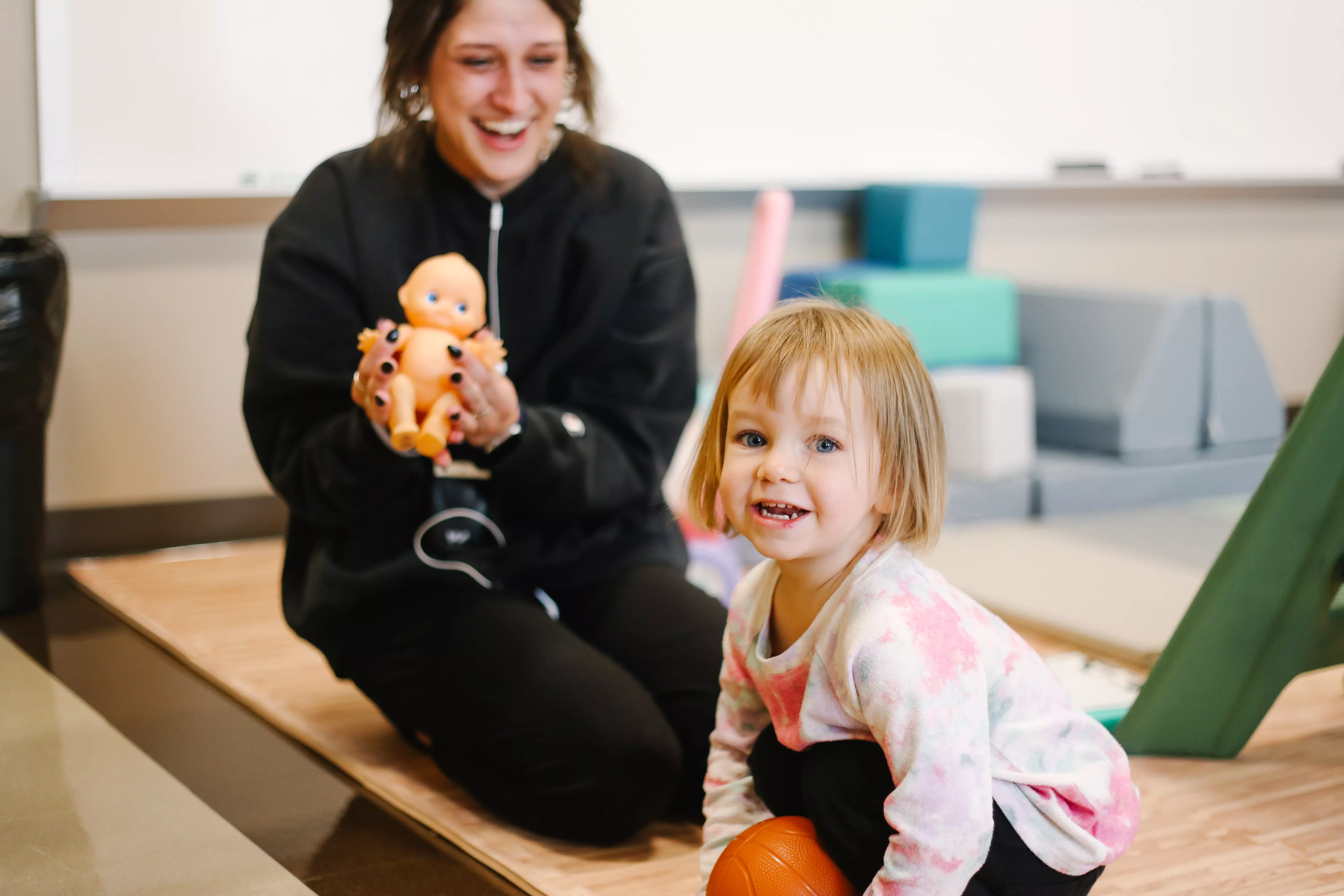 comms disorder student practice person centered care that benefits the community. a patient of a young age smiles happily as the student also smiles enjoying the work that is their passion