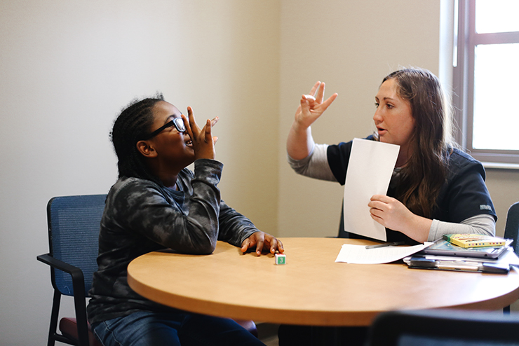  A Comm Disorder Student teaches a kid sign language.